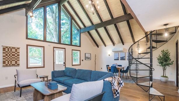 A spacious living room with a blue sofa, a dining area, and a spiral staircase.