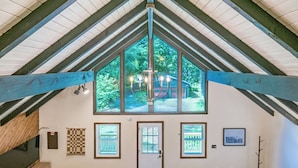 A room with a high ceiling, large windows, and a chandelier.