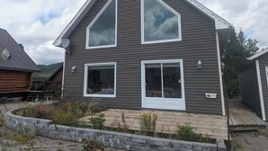 A two-story house with a dark siding exterior, large windows, and a visible address number.