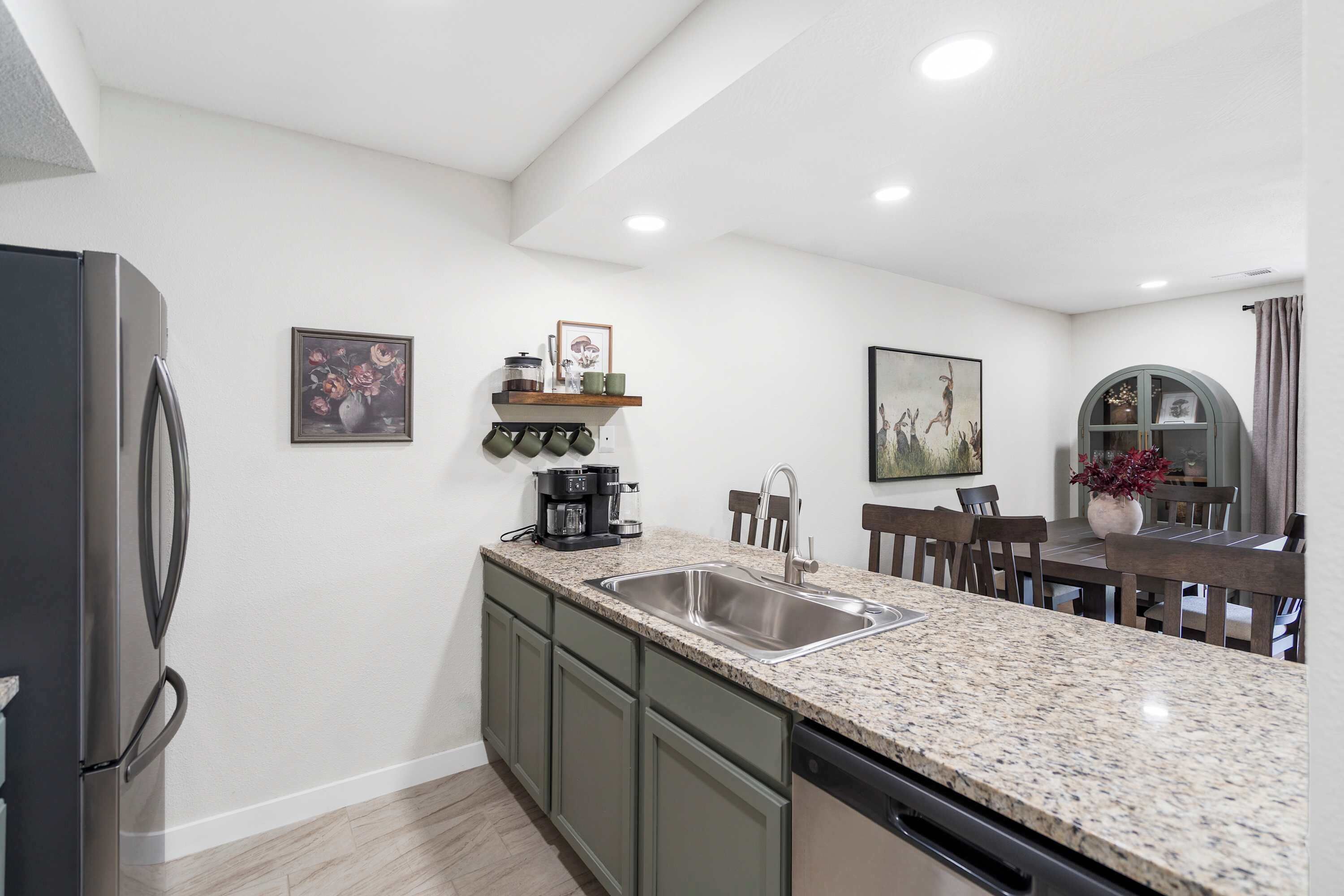 A modern kitchen with granite countertops, a built-in dishwasher, and a stainless steel refrigerator.