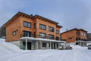 Um edifício de madeira de dois andares com entrada coberta e chão coberto de neve.
