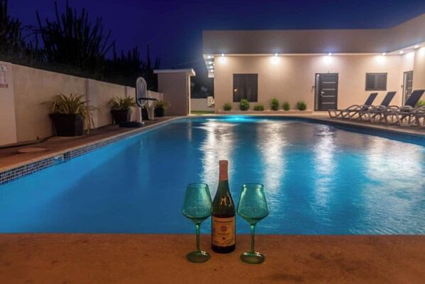 A swimming pool with lounge chairs and a bottle of wine.
