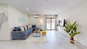 A modern living room with a sofa, coffee table, and a large potted plant.