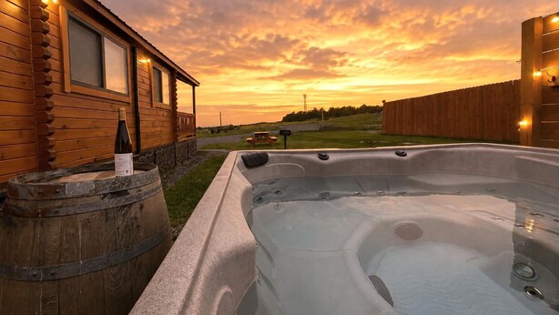 Een houten blokhut met een jacuzzi en een vat.