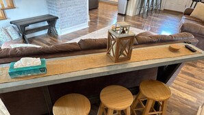 A kitchen island with stools, a bench, and a small table with a lantern.