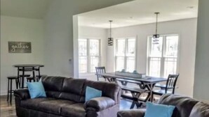 A spacious living room with two leather sofas, a patterned rug, and a dining area with a table and chairs.