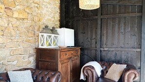 Um quarto acolhedor com parede de pedra, mobiliário de madeira e luminária pendente.