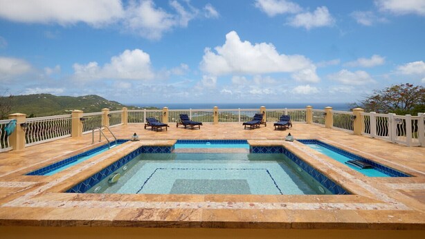 Une piscine sur le toit, avec quatre chaises longues et une vue sur l’océan.