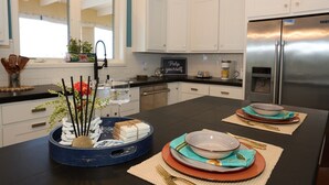 Une cuisine moderne avec des meubles blancs, un réfrigérateur en acier inoxydable et un plan de travail noir.