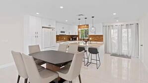 Una cocina moderna con armarios blancos, una isla central e iluminación colgante.