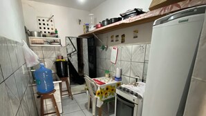 A compact kitchen with a refrigerator, stove, and a small dining table with chairs. - Apartment in Coroado, Manaus, close to buses, restaurants and markets. (Manaus)