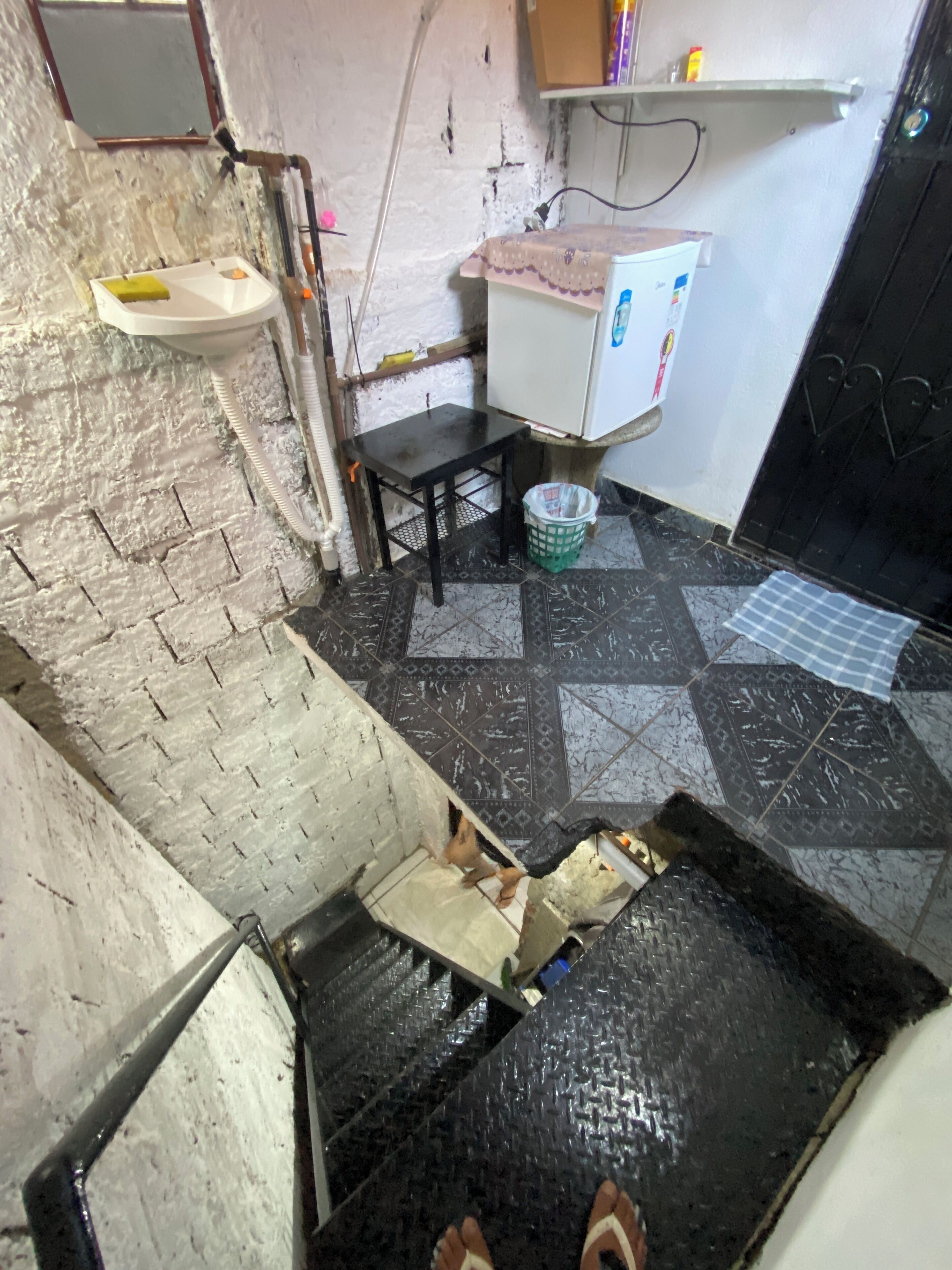 Una cocina con un lavamanos, un refrigerador y piso de baldosas.