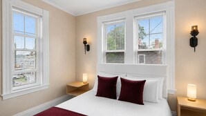 A bedroom with a large bed, two bedside tables, and two wall-mounted lamps. - The Witch City Hideout - Salem 3 Bedroom with Gameroom, Balcony & Free Parking (Salem)