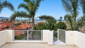 Un balcón con vista a un pueblo costero, palmeras y cielo despejado.