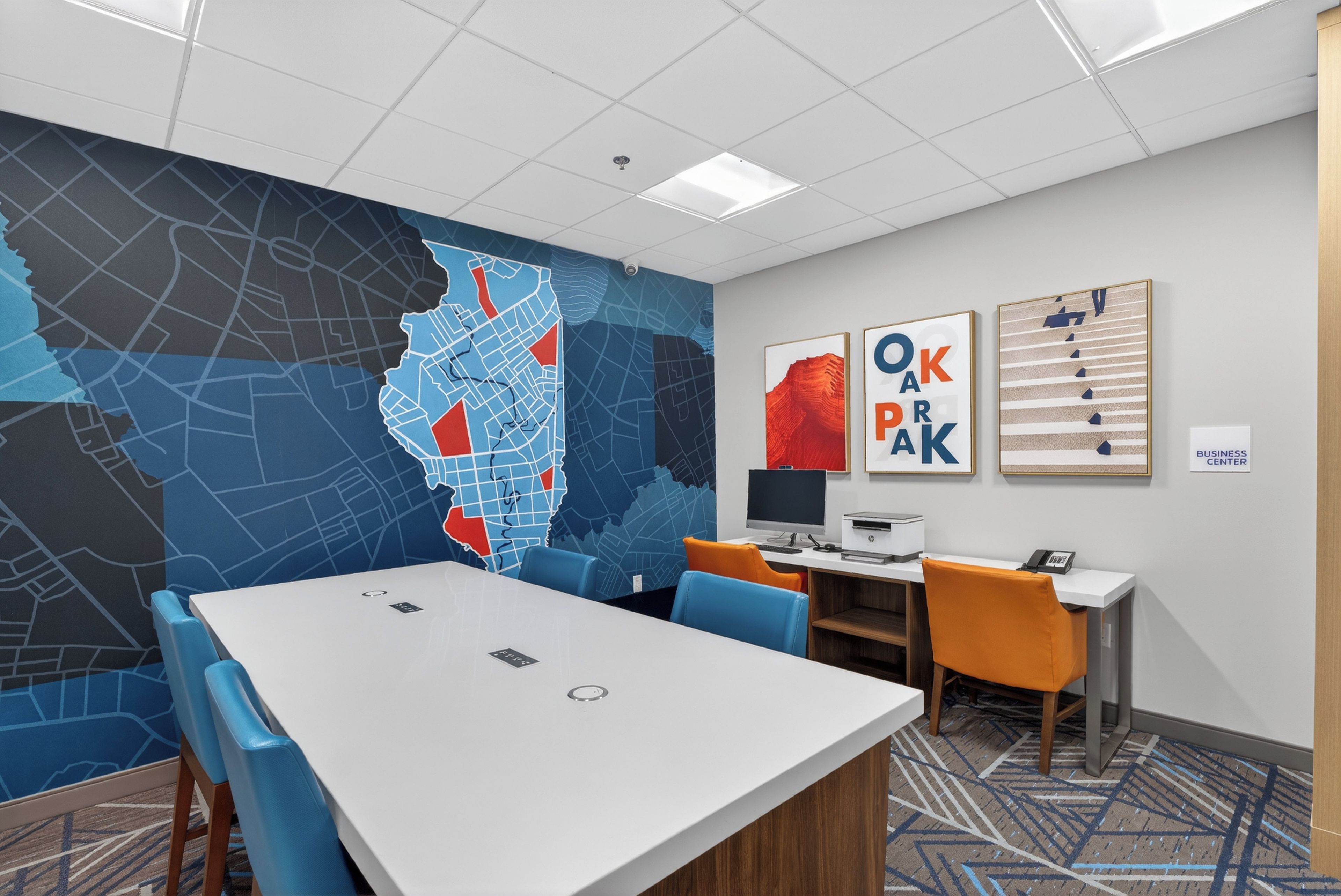 A conference room with a large table, chairs, a computer, and a map on the wall.