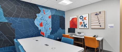 A conference room with a large table, chairs, a computer, and a map on the wall.