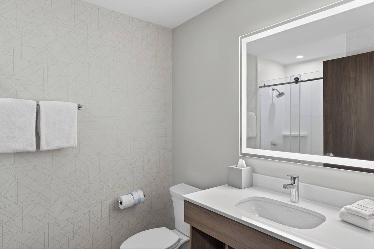 Un baño moderno con inodoro, lavamanos y ducha.