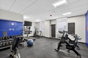 Une salle de sport équipée de matériel d’exercice, d’un tapis de course et d’un vélo d’appartement.