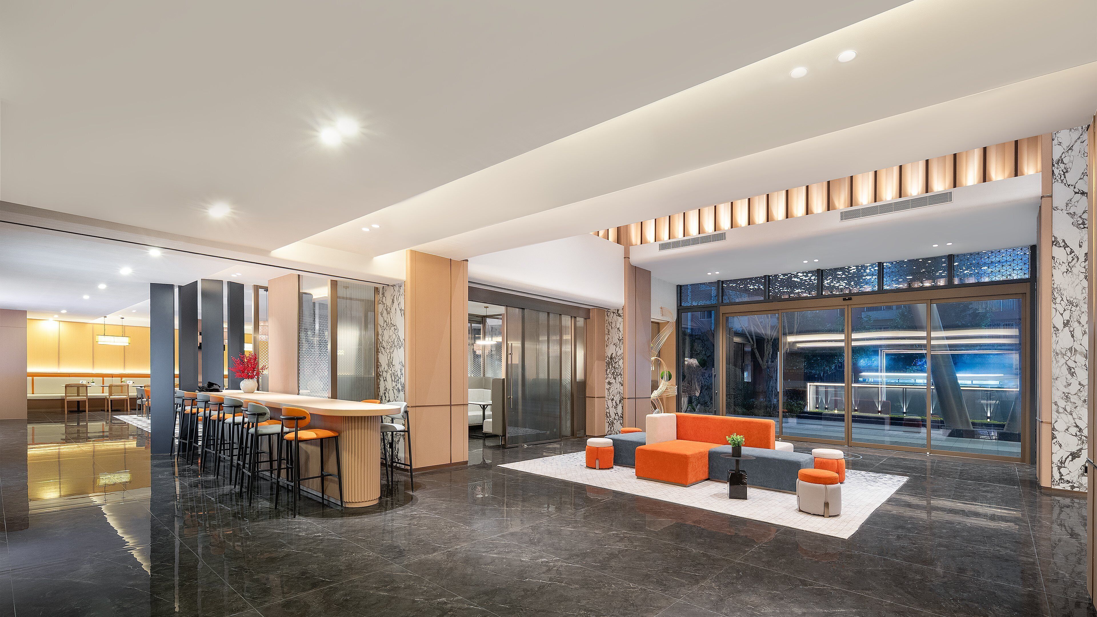 A modern lobby with a reception desk, seating area, and large windows offering views of the outside.
