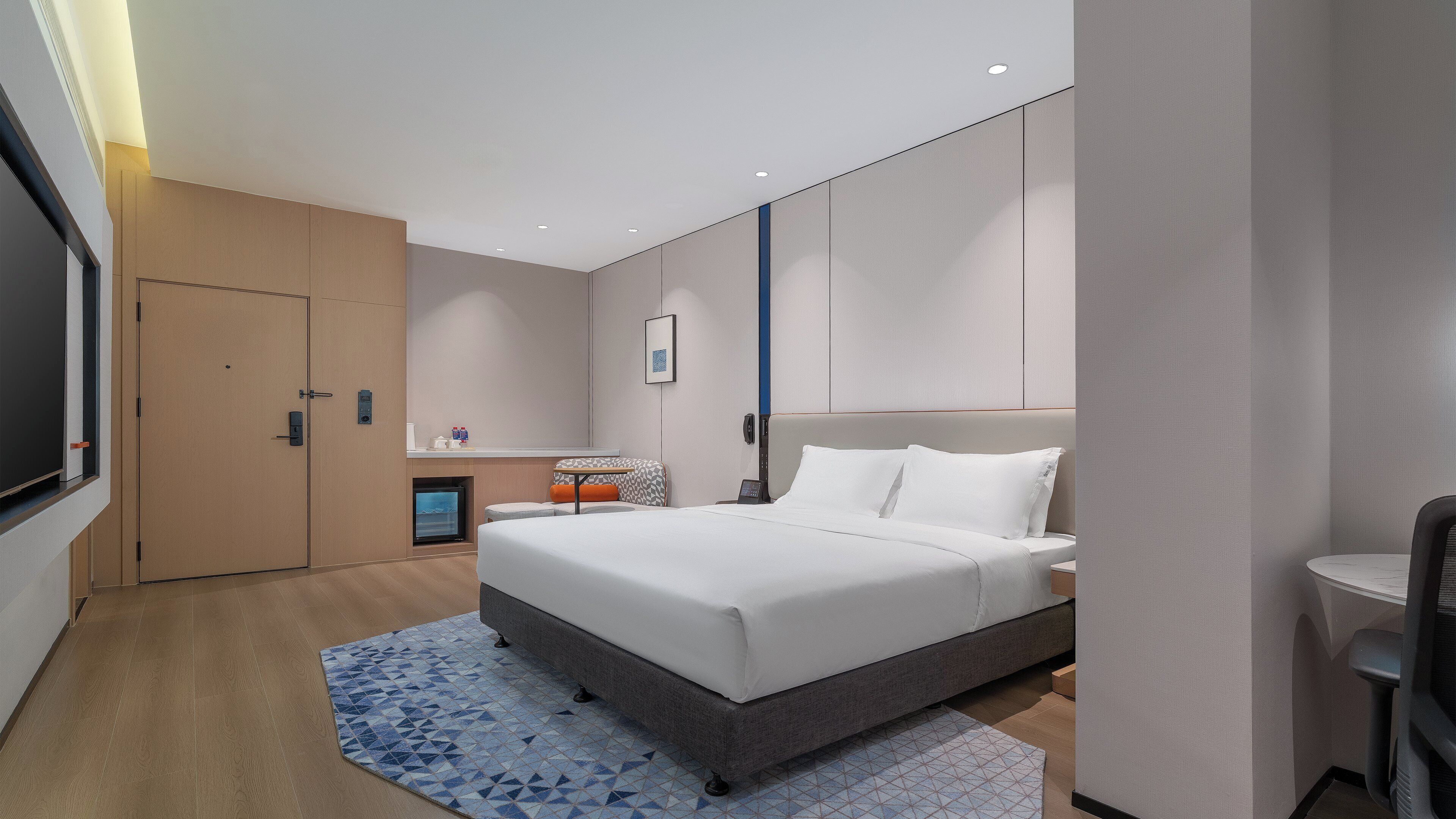 Una camera d'albergo moderna con un letto grande, una scrivania, una sedia e un televisore.