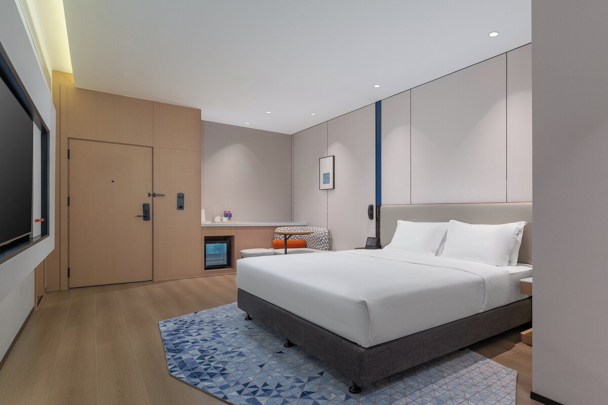 Een moderne hotelkamer met een groot bed, een klein bureau, een stoel en een televisie.
