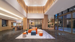 Een moderne lobby met een receptiebalie, een zithoek en een glazen wand met uitzicht op de stad.