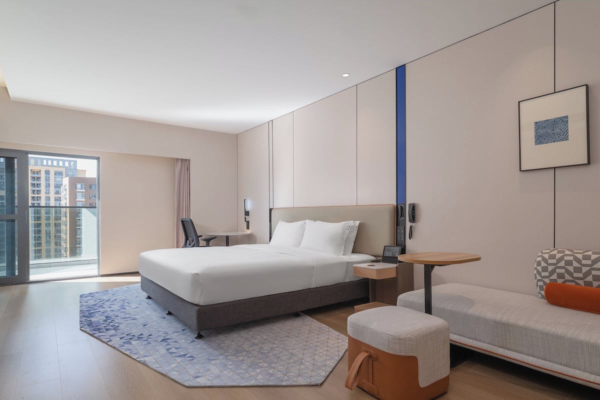 Ein modernes Hotelzimmer mit einem großen Bett, einem Schreibtisch, einem Stuhl und einer Couch.
