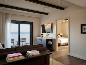A modern hotel room with a balcony, a sofa, a desk with books, and a bed.