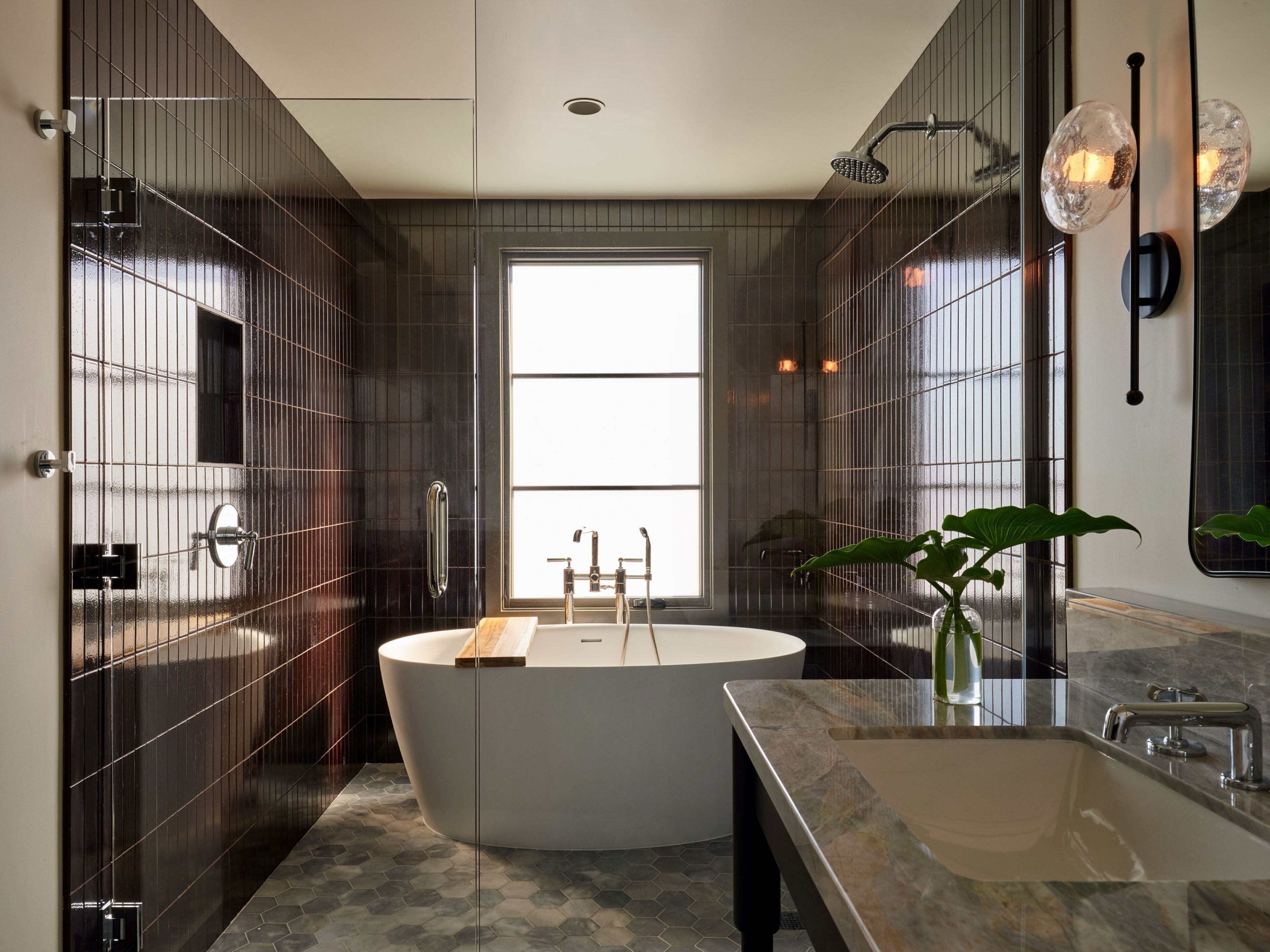 A modern bathroom with a freestanding bathtub, a large mirror, and a sink with a marble countertop.