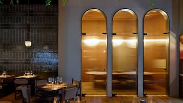 L’intérieur d’un restaurant, avec des tables dressées pour le service, un mur recouvert de carreaux et un ascenseur moderne.