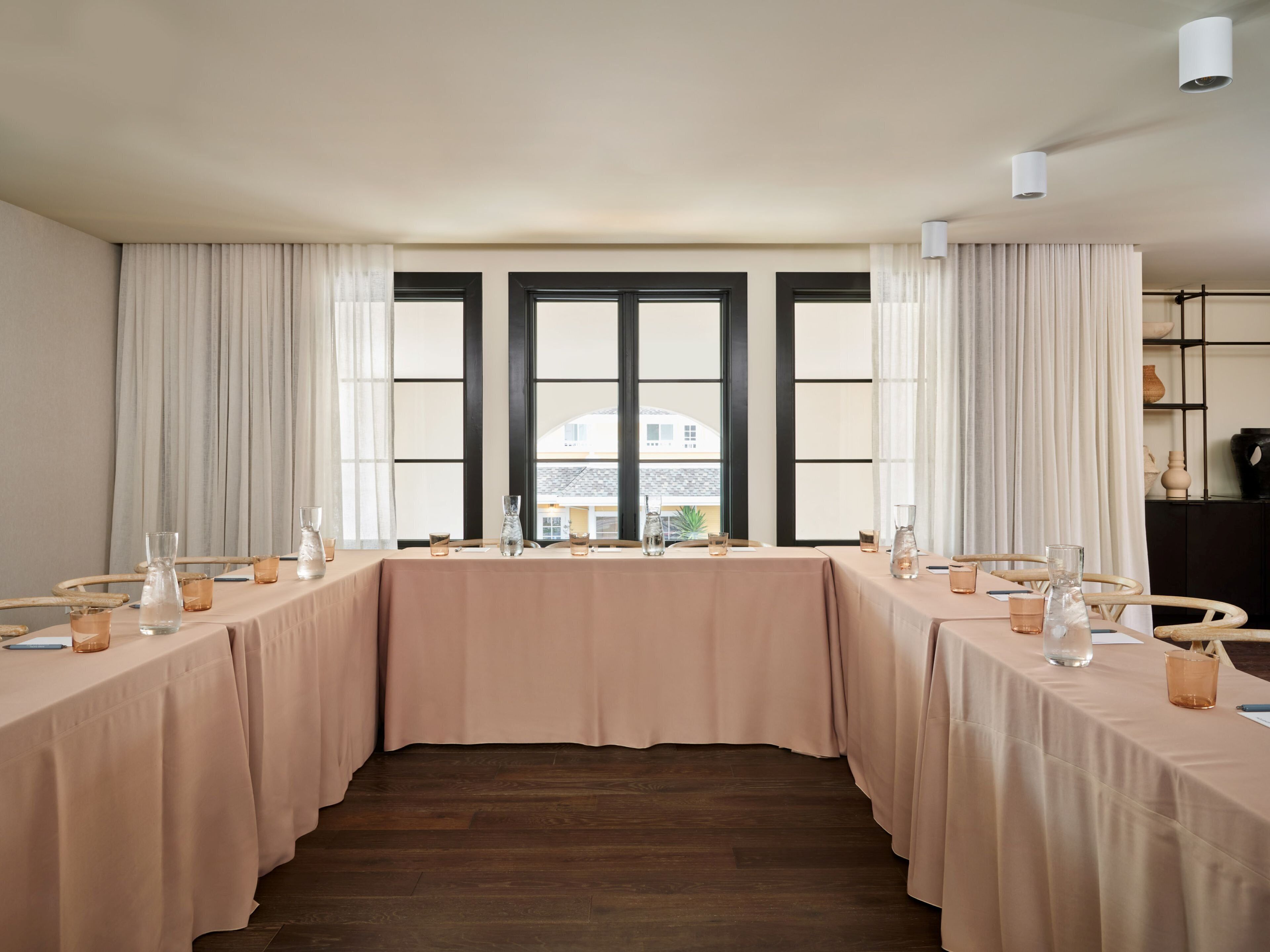 A conference room with a long table, chairs, and a view through large windows.