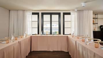 Un salón de conferencias con una larga mesa, sillas y vistas amplias a través de ventanas grandes.