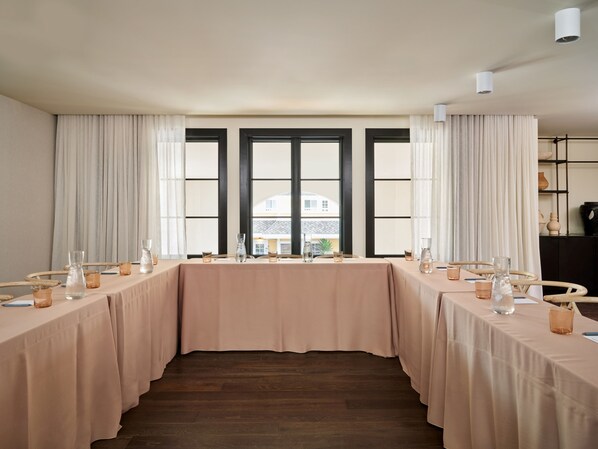 Un salón de conferencias con una larga mesa, sillas y vistas amplias a través de ventanas grandes.