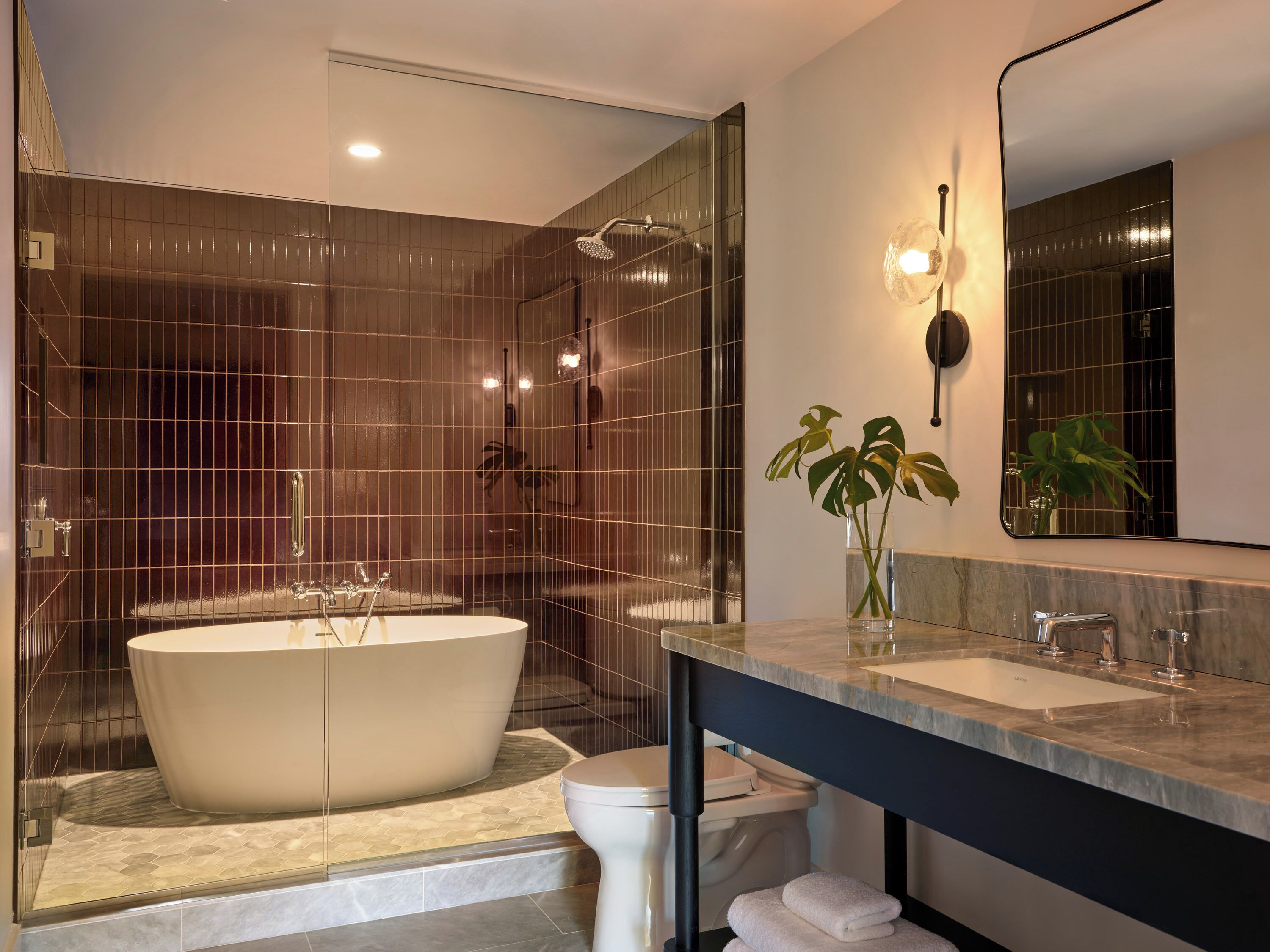 A modern bathroom with a freestanding bathtub, a large mirror, and a shower enclosure.