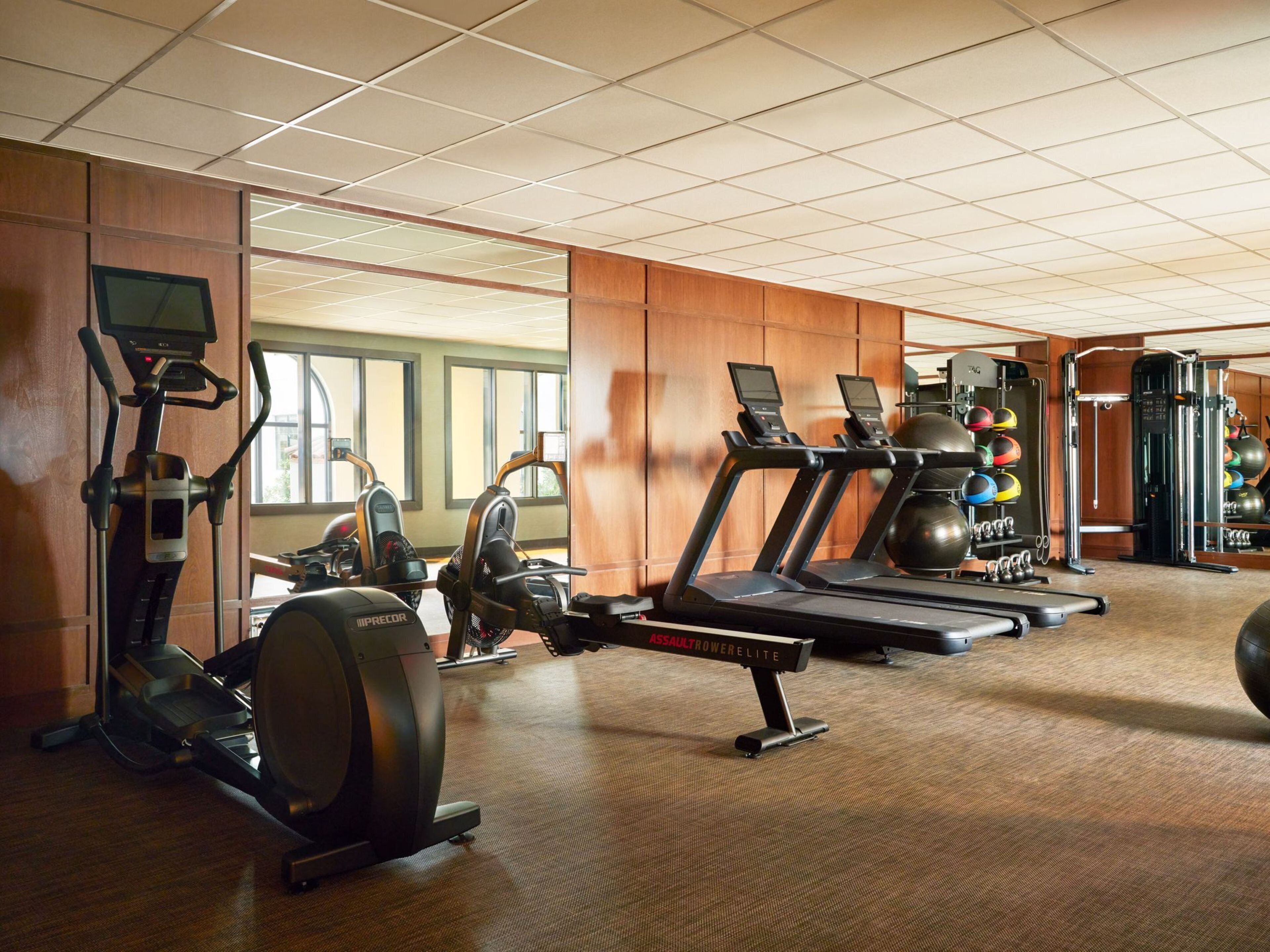 Un gimnàs amb cintes de córrer, el·líptiques i equipament de musculació.