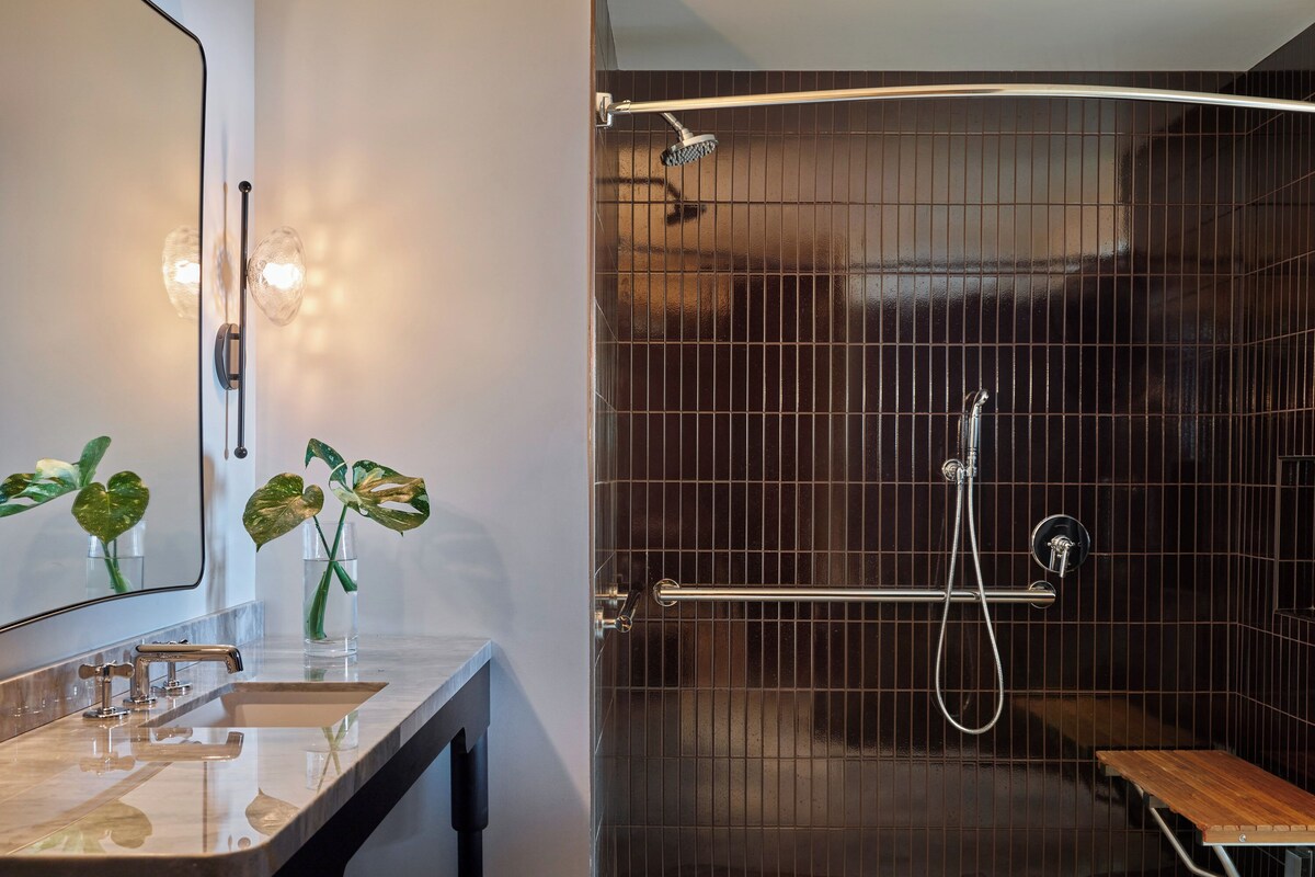 A modern bathroom with a vanity, mirror, and two potted plants.