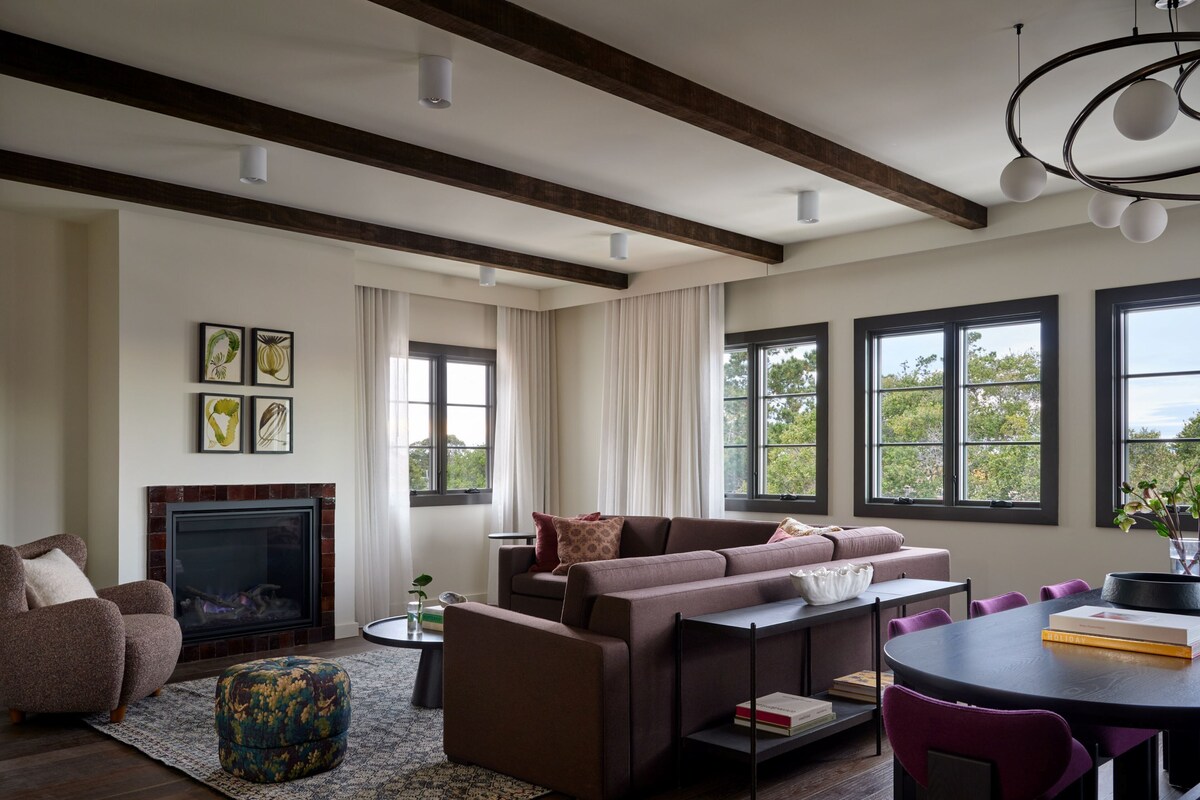 A modern living room with a fireplace, a sofa, a coffee table, and a dining area with chairs.