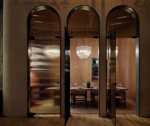 A modern dining area with a chandelier, wooden tables, and chairs. - Kimpton Mirador Pacific Grove Monterey by IHG (Pacific Grove)