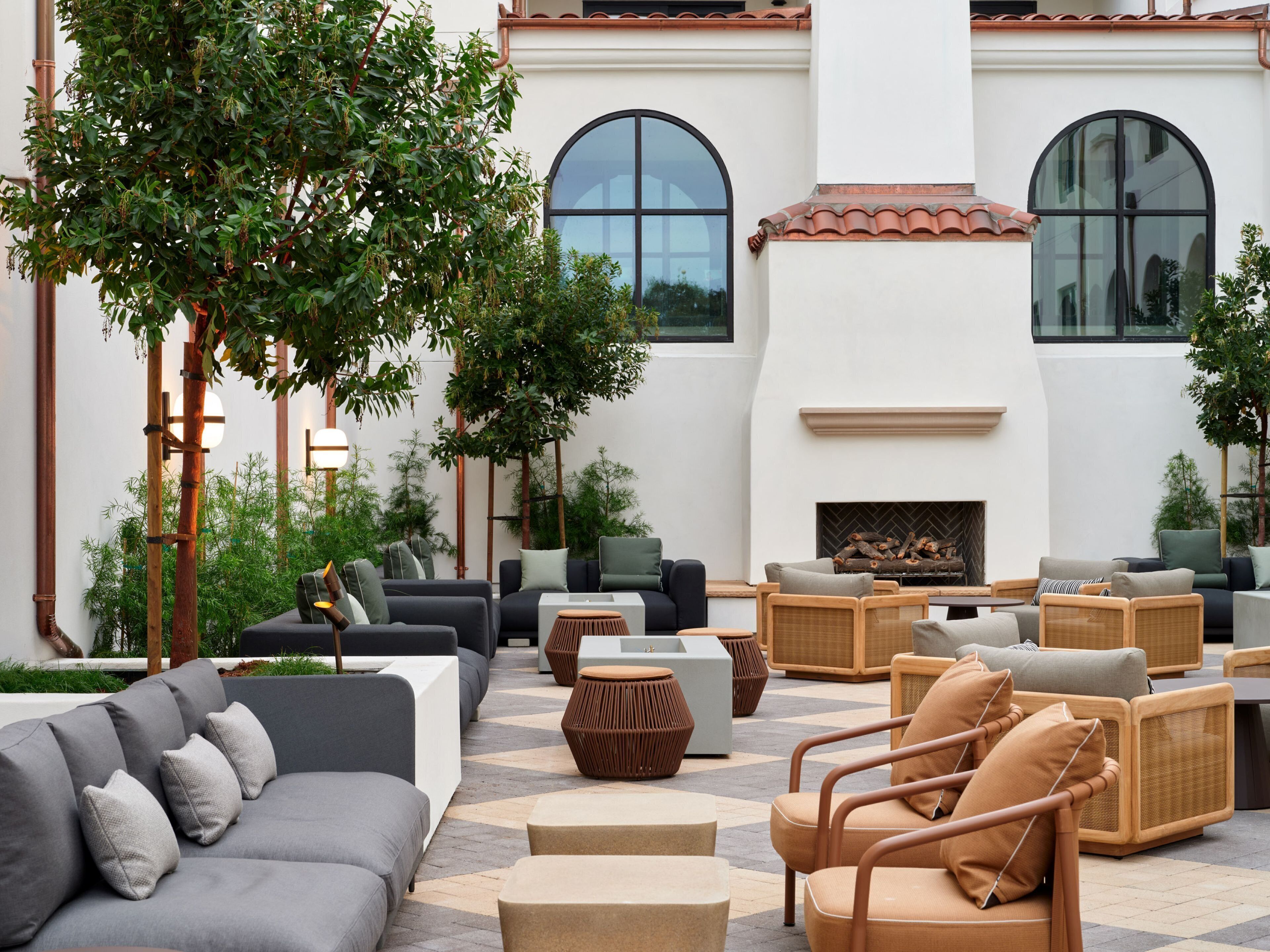 An outdoor patio area with modern furniture, a fireplace, and large windows.