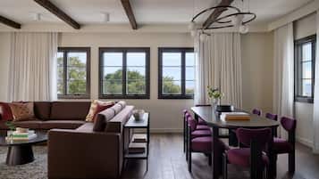 A modern living room with a brown sofa, a dining table with purple chairs, and large windows with curtains.