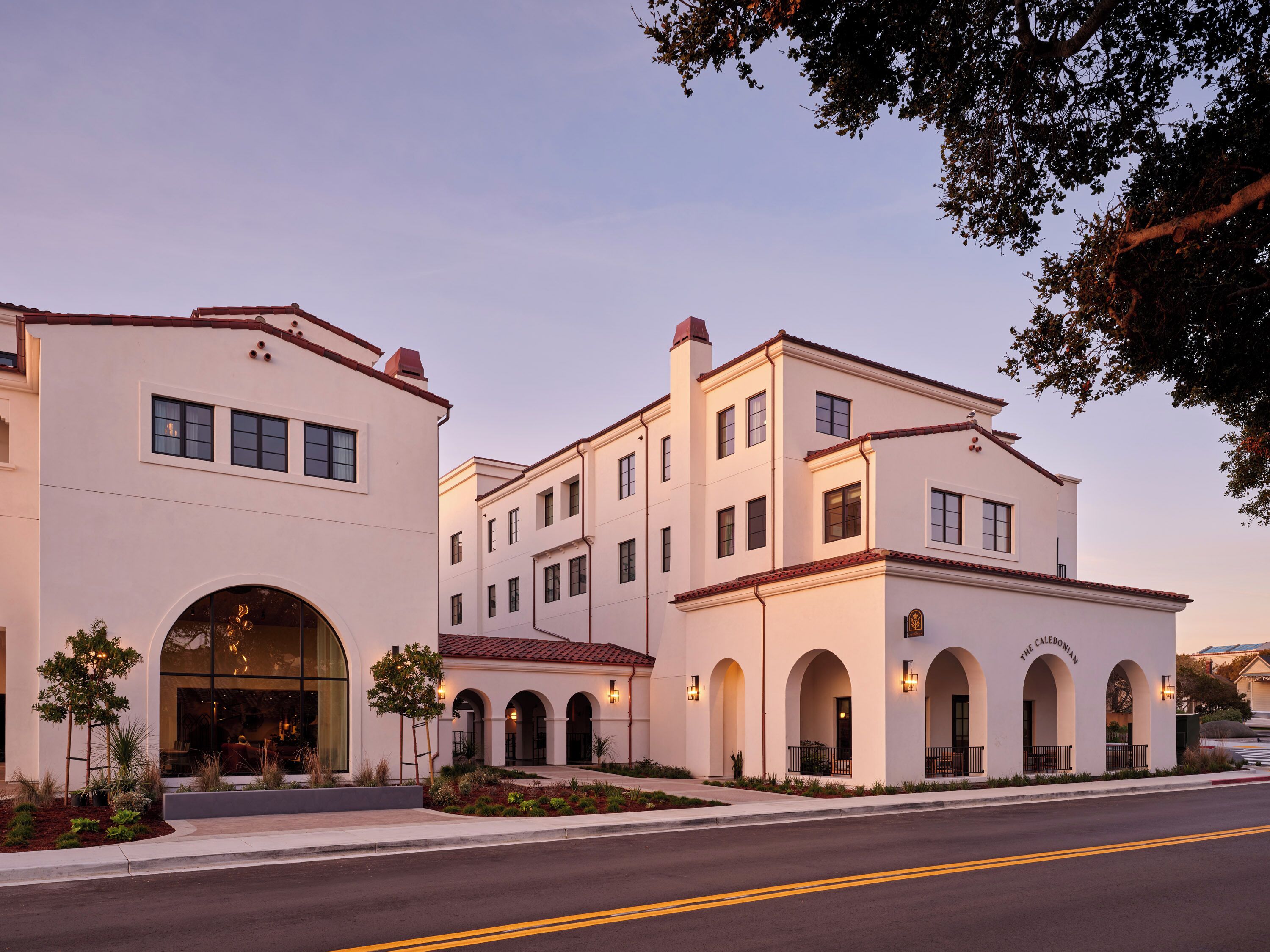 A two-story building with a white facade, multiple windows, and a central entrance with an arched doorway.
