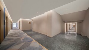 A modern hotel corridor with a patterned carpet, recessed lighting, and a view into the distance. - Holiday Inn Express Qingdao Downtown by IHG (Qingdao)