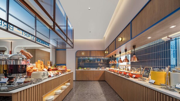 A modern buffet setup with multiple food stations, a clear view of the kitchen area, and a spacious layout. - Holiday Inn Express Qingdao Downtown by IHG (Qingdao)