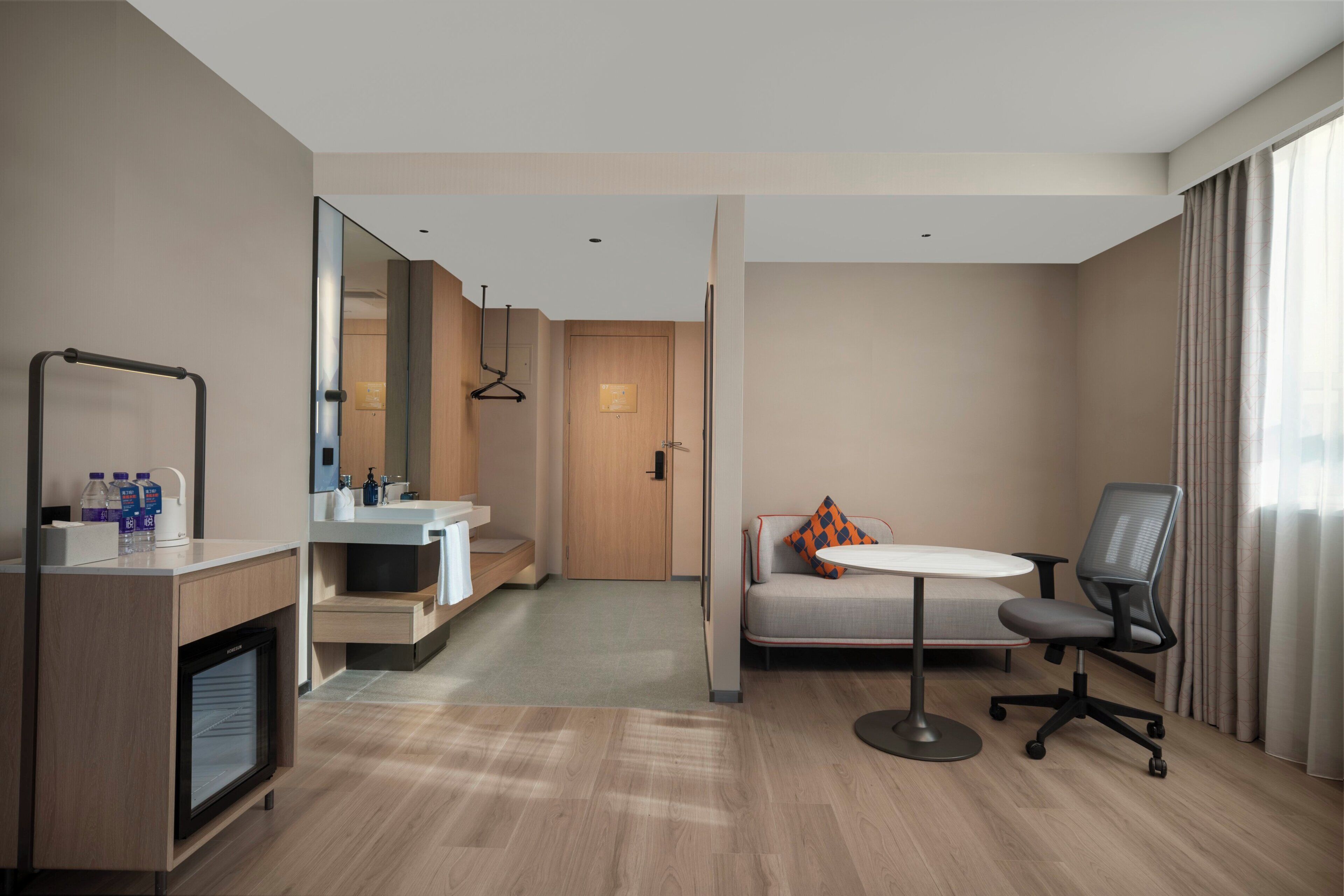 Une chambre d’hôtel moderne équipée d’une kitchenette, d’un canapé, d’une petite table et d’une chaise.