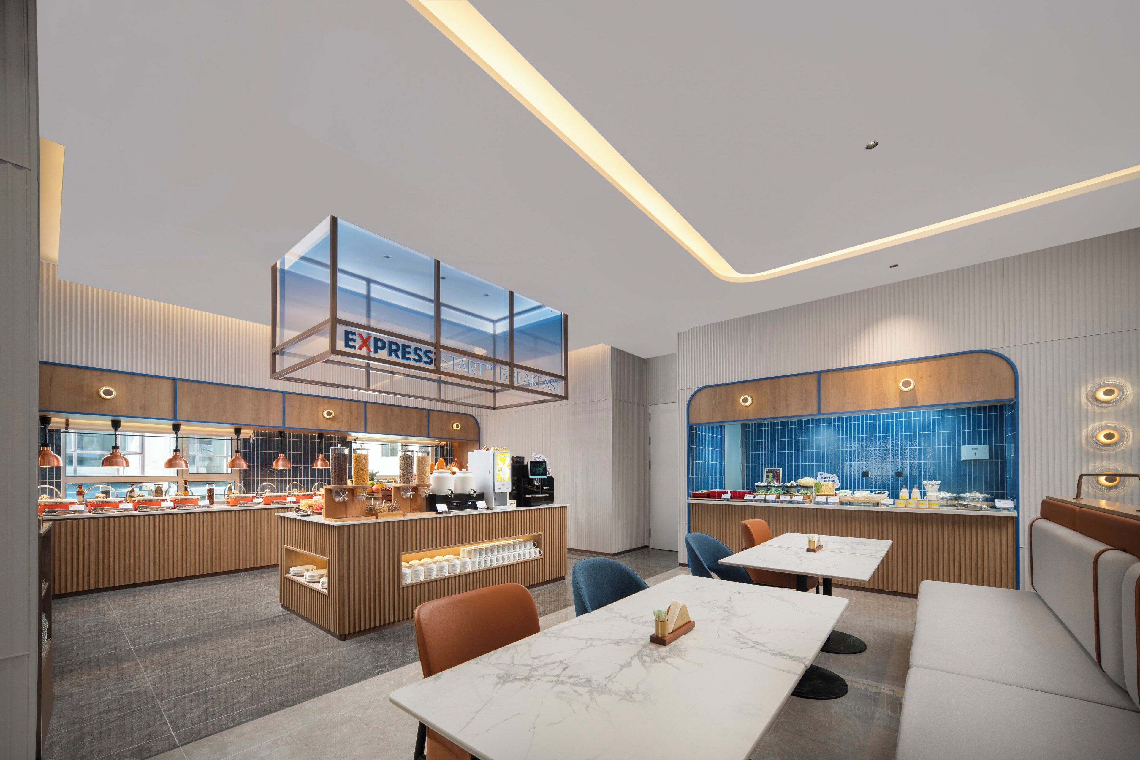 A modern restaurant interior with a central Express counter, seating area with tables and chairs, and a kitchen visible through a glass partition.