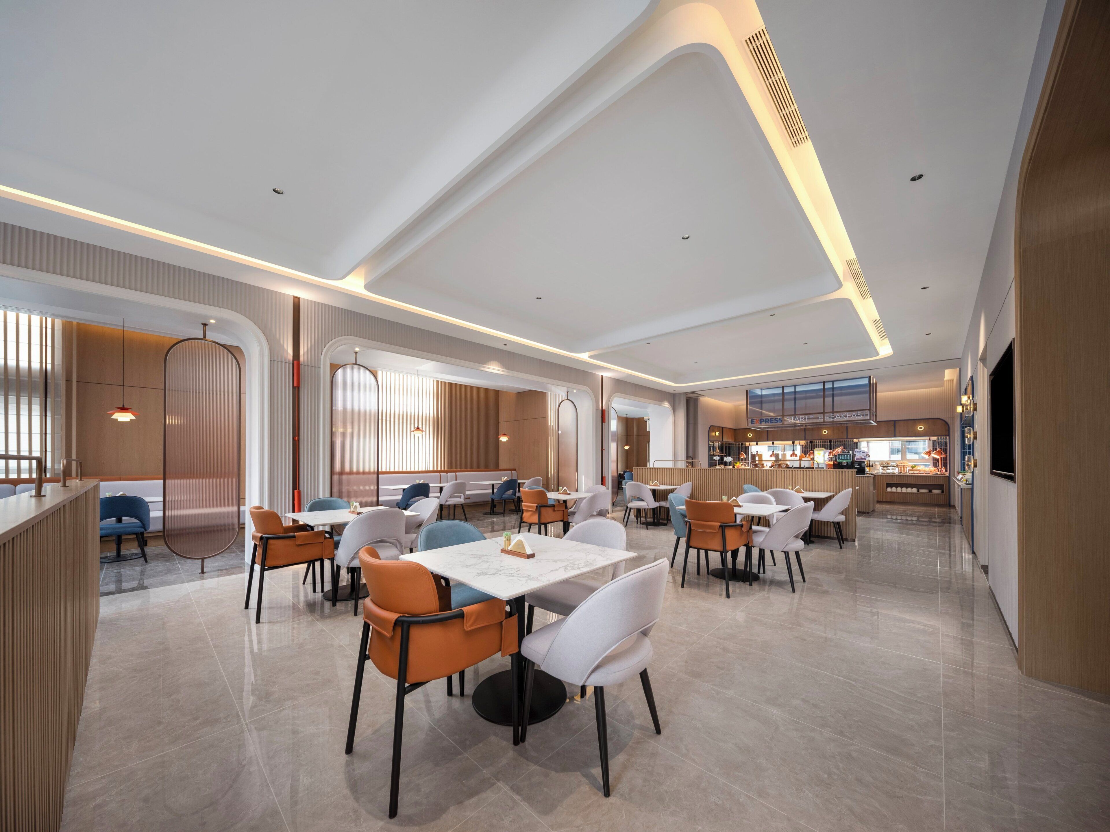 A modern restaurant with a clean, minimalist interior, featuring a mix of seating arrangements and a central dining area.