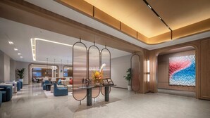 A modern lobby with a reception desk, seating area, and a large wall art piece. - Holiday Inn Express Qingdao Downtown by IHG (Qingdao)