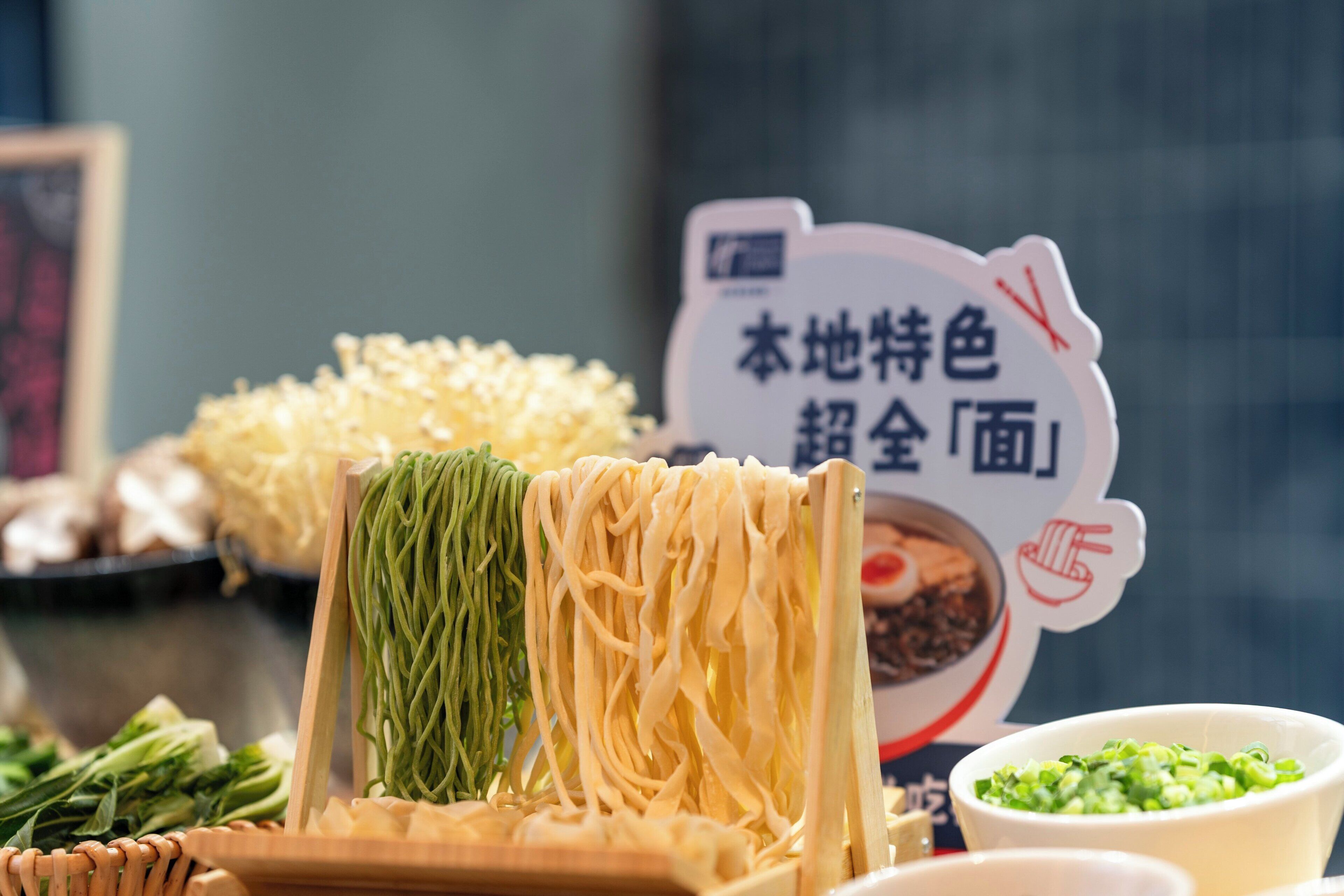 Una variedad de fideos y verduras, incluyendo fideos verdes y amarillos, bok choy y champiñones.
