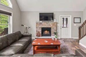A living room with a fireplace, a leather sofa, a coffee table, and a telescope.