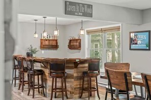 A bar area with a rustic wooden bar counter and multiple stools.